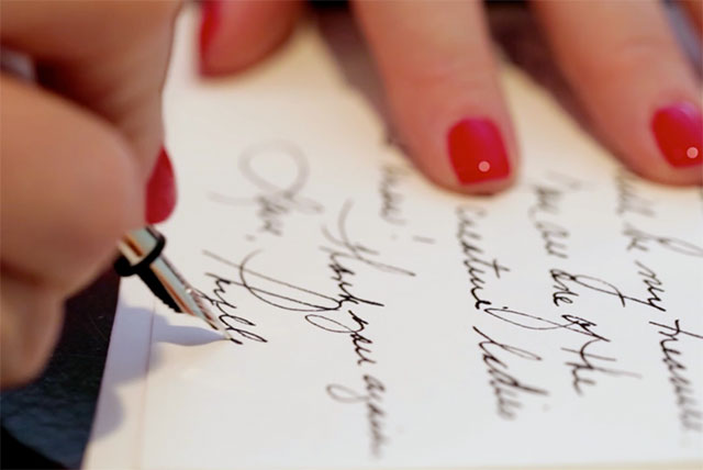 A photo of a woman signing a letter