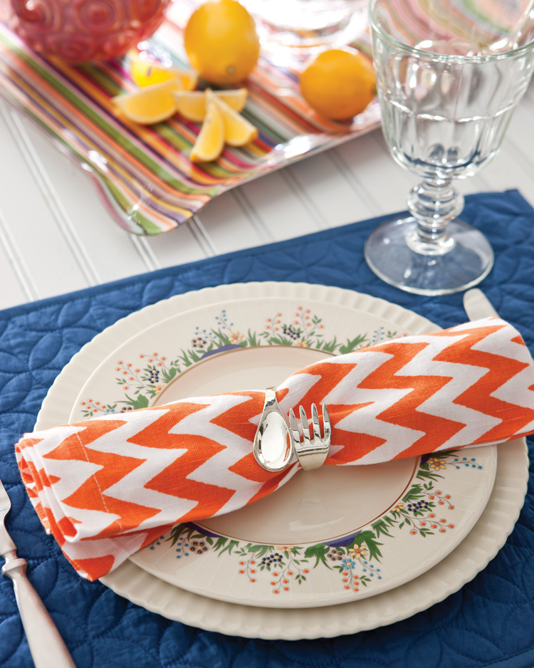 A photo of a an orange-and-white chevron napkin and the Lenox Rutledge china pattern.