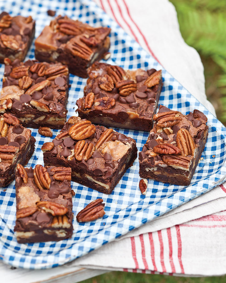 Caramel and pecan topped brownies on a gingham tray