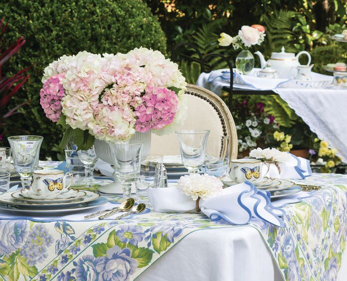 Spring tablescape set in a garden with pink and white hydrangeas as the centerpiece