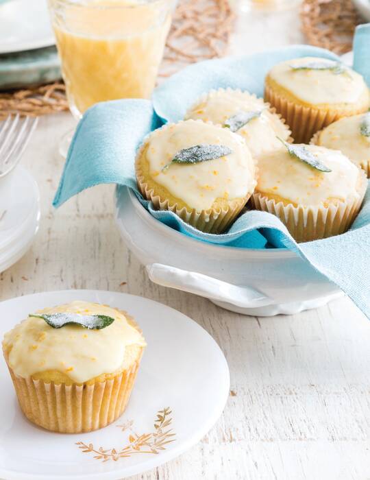 Orange Sage Muffins, one on a white plate and 5 in an aqua linen-lined white bowl