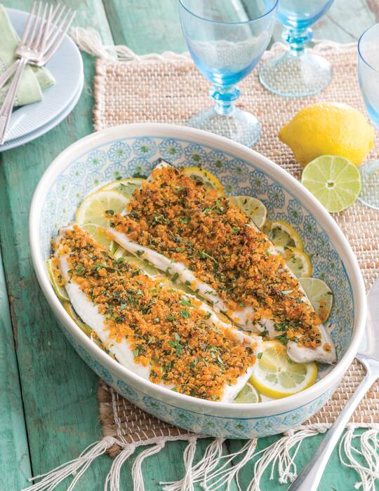 Two Herb-Crusted Trout filets served in a large decorative blue, white, and green bowl