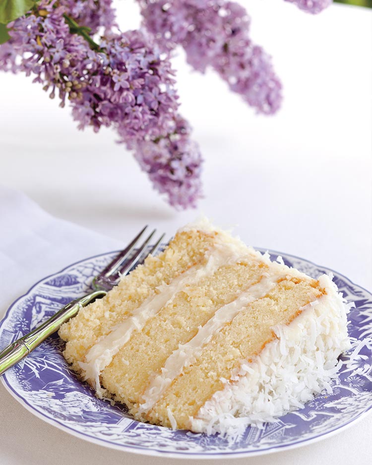 Slice of layered coconut cake on a purple-and-white plate