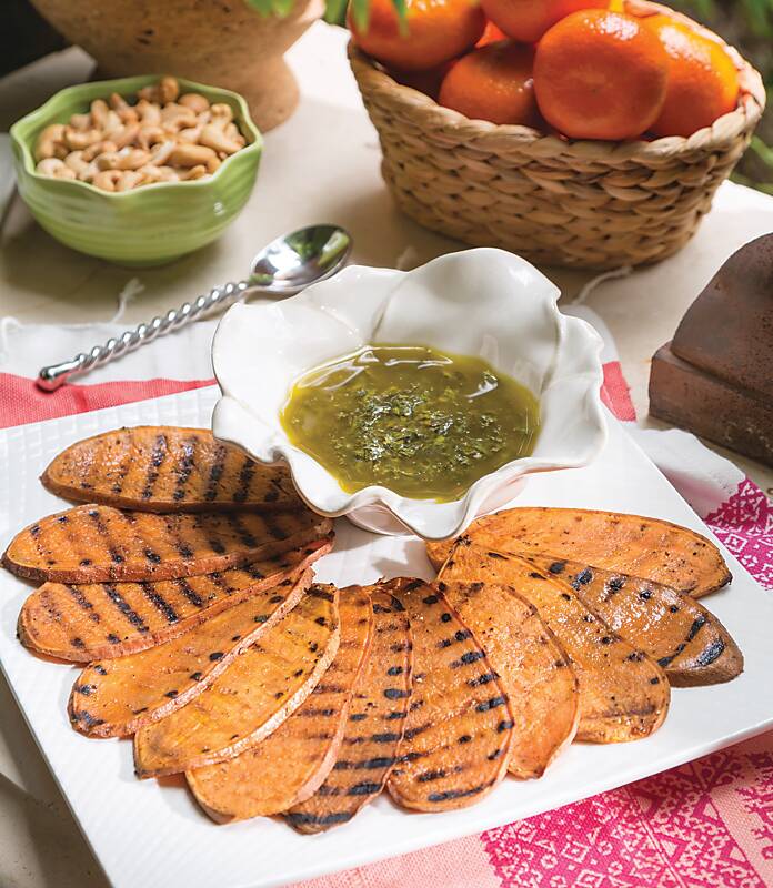Grilled Sweet Potato Slices fanned out on a white platter with a bowl of Mint Chimichurri
