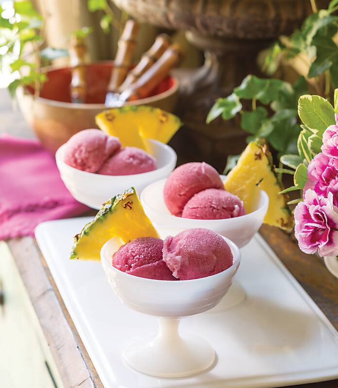 Pink sorbet in white bowls with pineapple slices