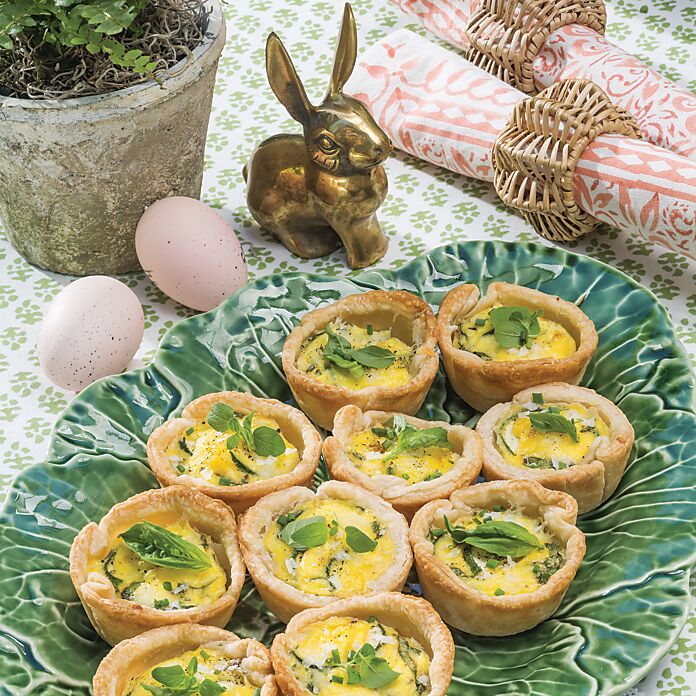 Mini herb-topped quiches on a green cabbage-motif platter