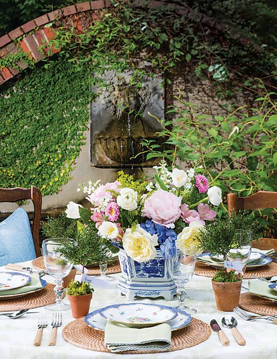 Tabletop of blue, pink, and green accents in front of a moss-covered garden fountain