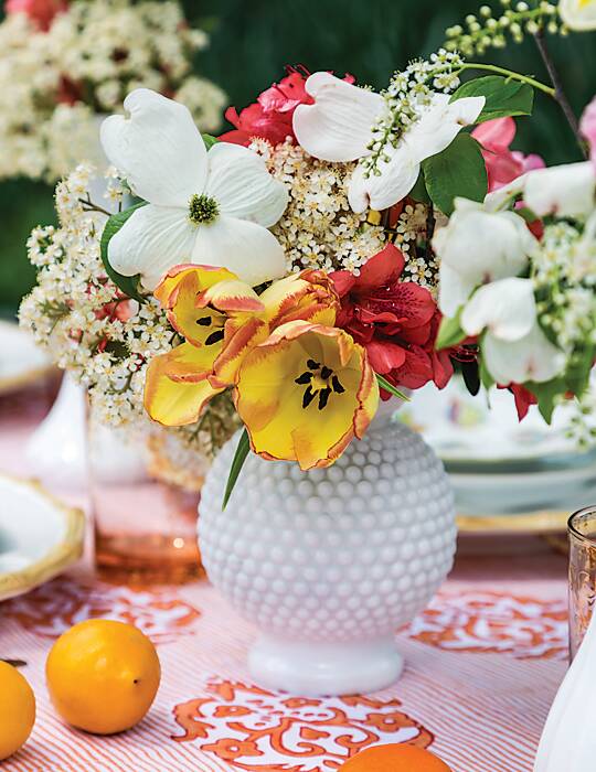 Pink, white, and yellow flowers in a hobnail milk glass vase
