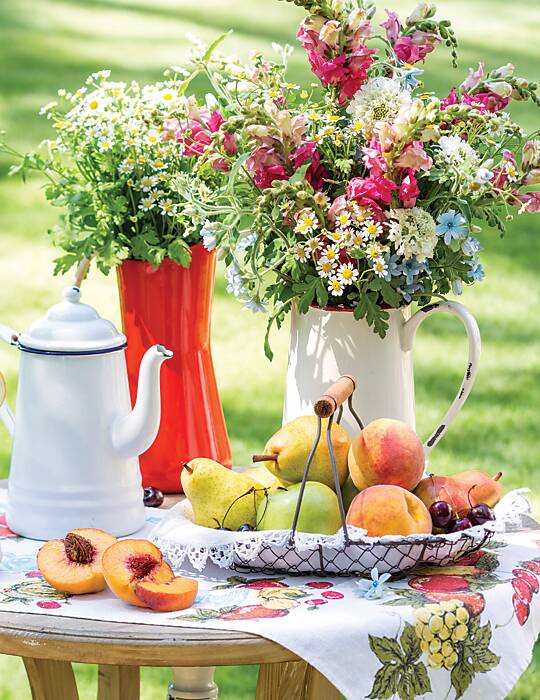 Two wildflower bouquets in vintage containers and a basket of fruit