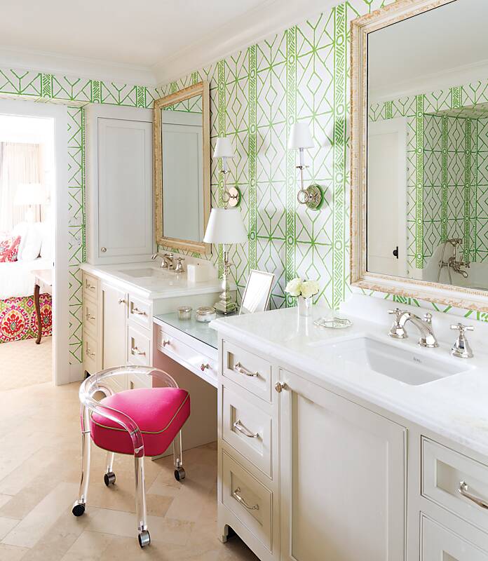 Bathroom with green-and-white trellis wallpaper and acrylic vanity chair with pink seat