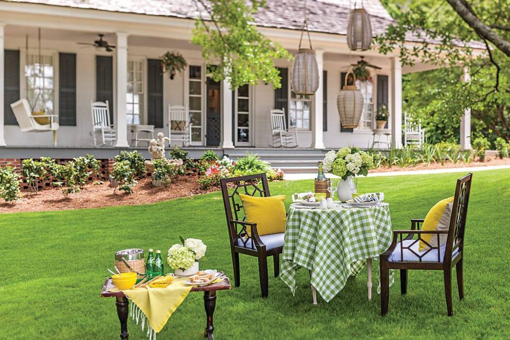Outdoor table decorated in shades of green, yellow, and white in front of a white house