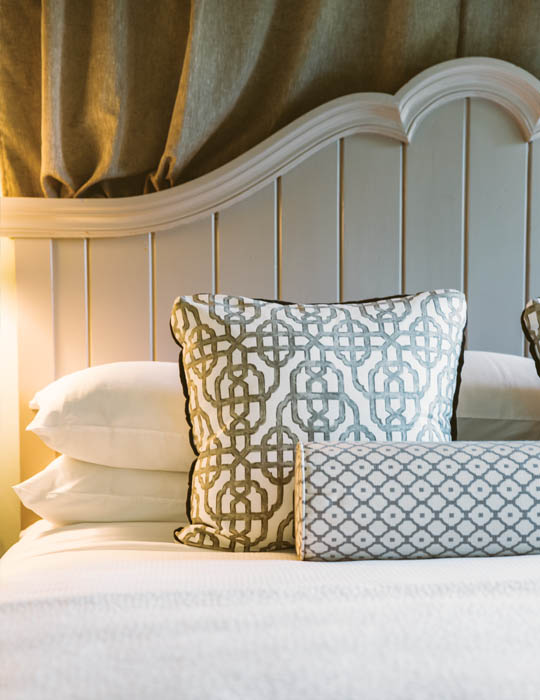 A close-up view of decorative pillows and a scalloped headboard at The Fearrington House Inn