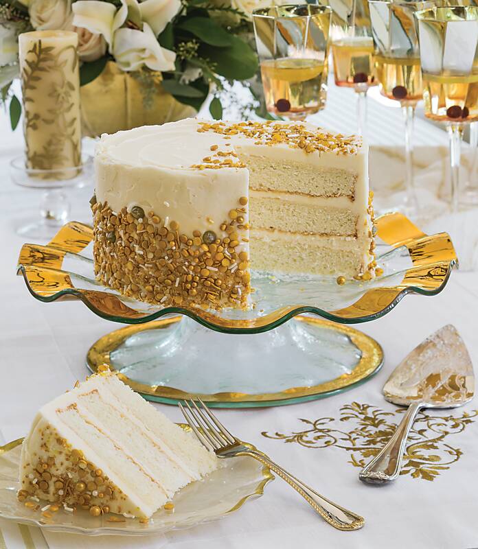 Vanilla layer cake with gold sprinkles on a ruffled cake stand