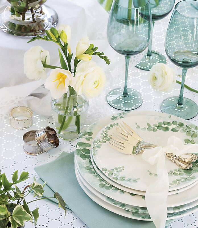 Table setting with blue glassware and white china embellished with eucalyptus motif