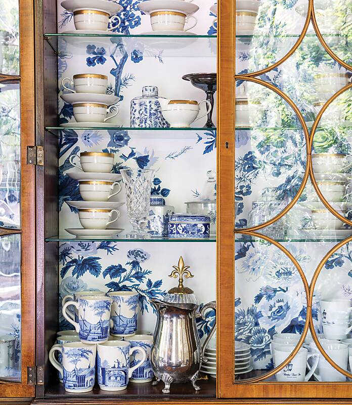 Blue-and-white tableware in a china cabinet lined with blue-and-white wallpaper