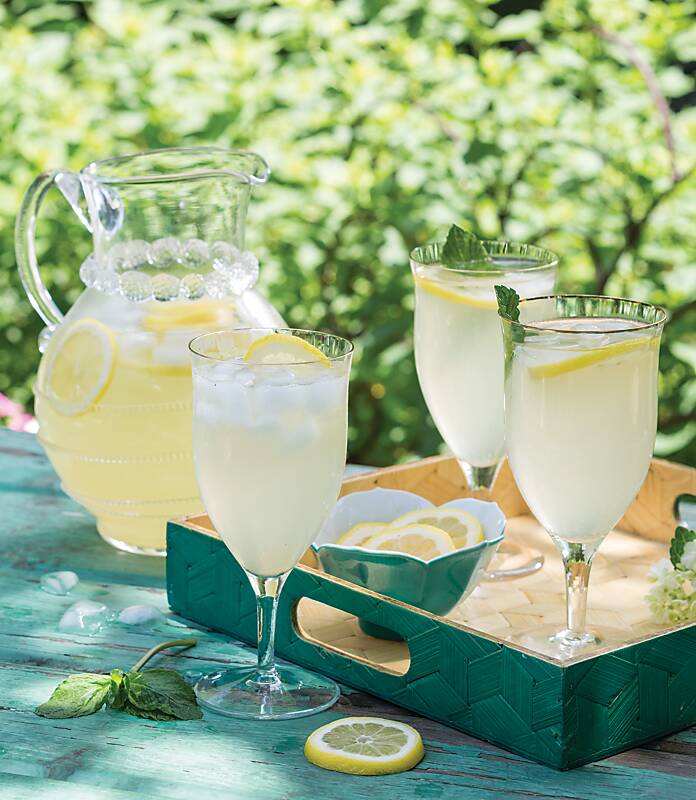 A clear pitcher and three stemmed glasses of lemonade 