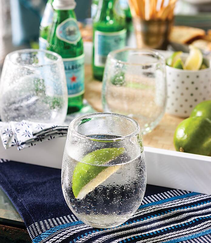 Stemless wineglasses filled with sparkling water and lime wedges