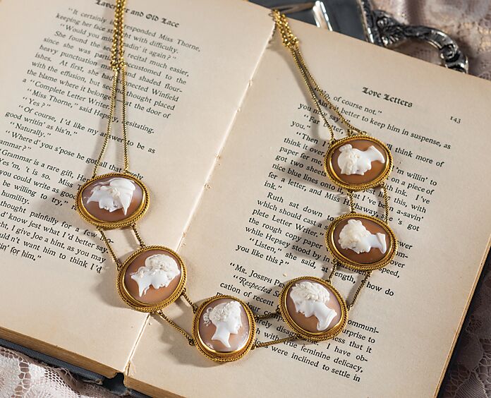 Beautiful cameos strung on a necklace atop an open book