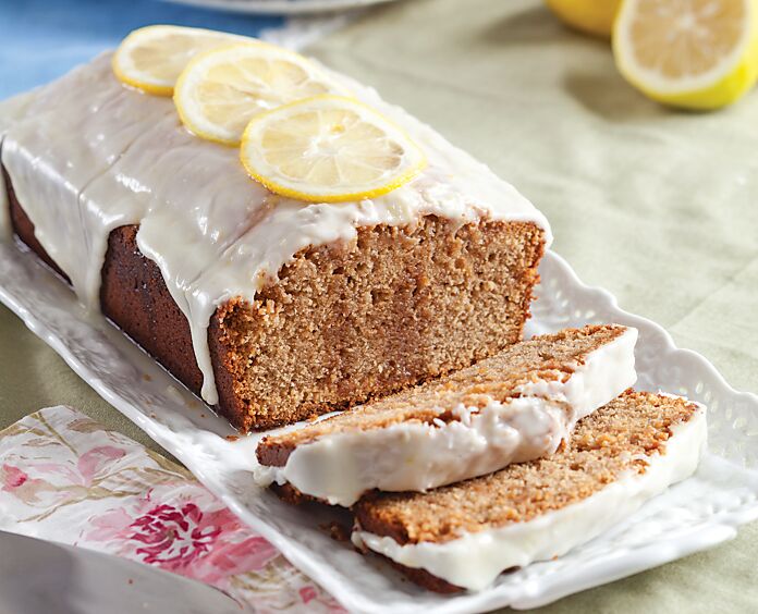 A loaf of Sweet Tea Poke Pound Cake garnished with a white glaze and lemon slices