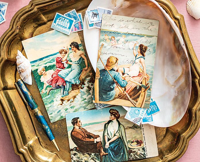 Assorted seaside-themed antique postcards on a gold tray