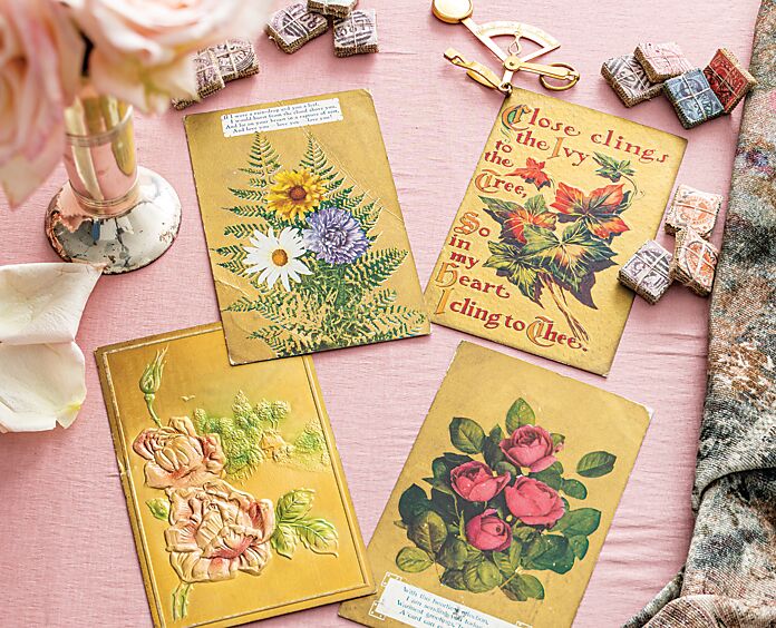 Four antique gold floral postcards on a pale pink backdrop