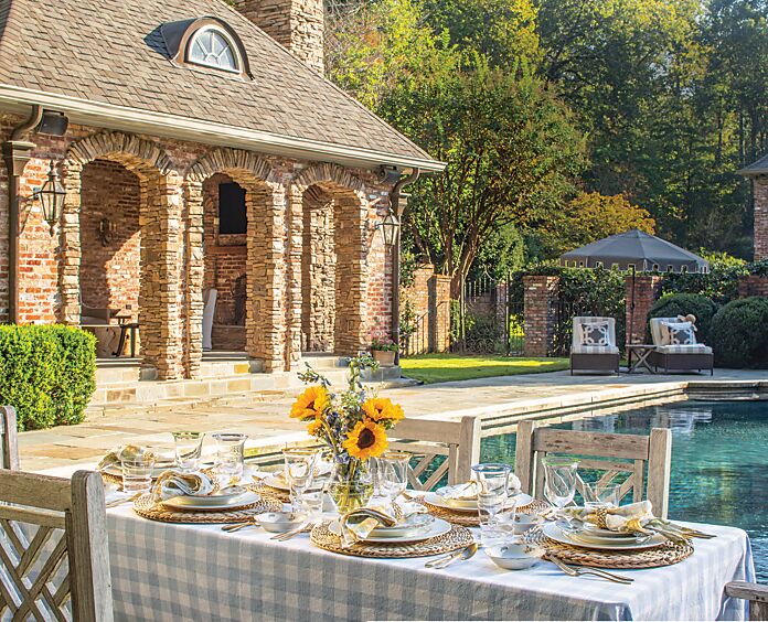 A poolside tablescape anchored by blue-and-white gingham and sunflowers
