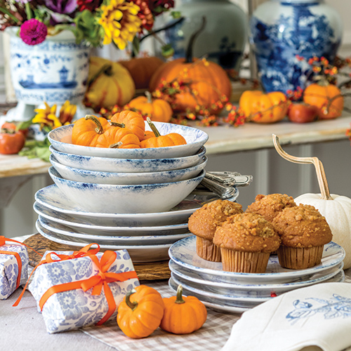Stacks of blue-and-white dinnerware topped with muffins and mini pumpkins