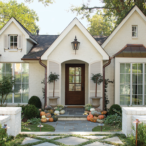 A cream-colored home exterior adorned with pumpkins